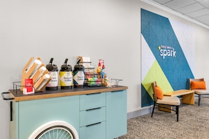 A coffee station with various beverages and a wall with a geometric design and the text 'It only takes a spark.'