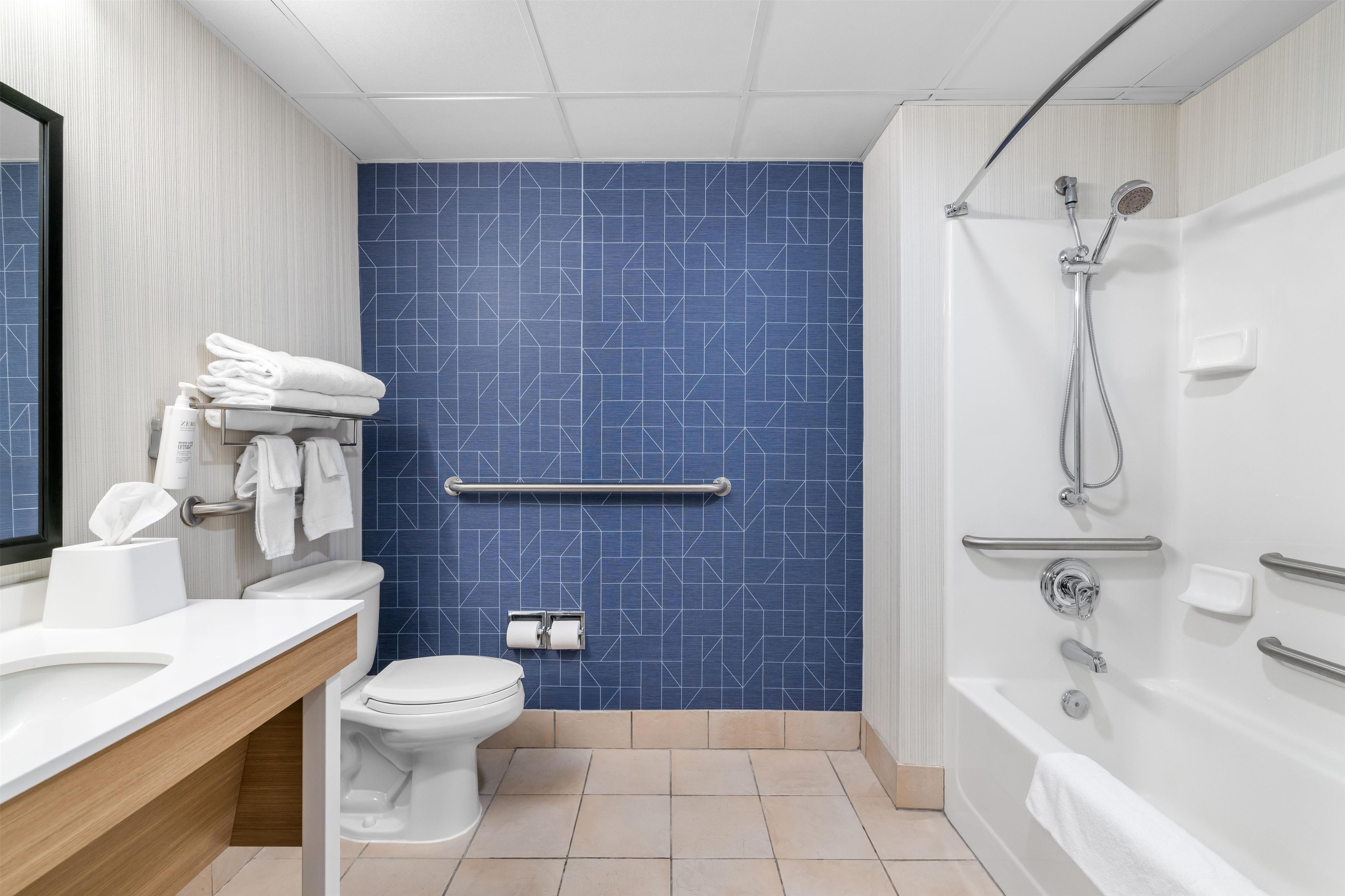 Een moderne badkamer met een blauw patroon op de muur, een wit toilet, een wastafel met spiegel en een douchehoek.