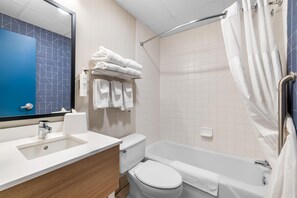 Un baño con lavamanos, inodoro, bañera y un perchero con toallas dobladas.