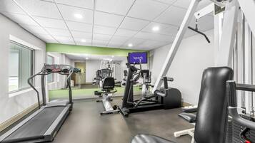 A gym with a treadmill, weight machines, and a TV screen displaying 'spark'.