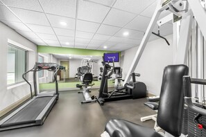 A gym with a treadmill, weight machines, and a TV screen displaying 'spark'.