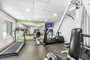 A gym with a treadmill, weight machines, and a TV screen displaying 'spark'.