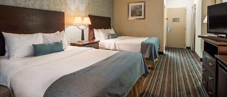 A hotel room with two beds, a TV, a lamp, and a door leading to another room.