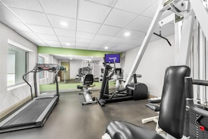 A gym with a treadmill, weight machines, and a TV screen displaying 'spark'.
