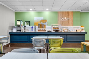 A breakfast bar with seating, a coffee machine, and a sign that reads 'Delight in the Day.'