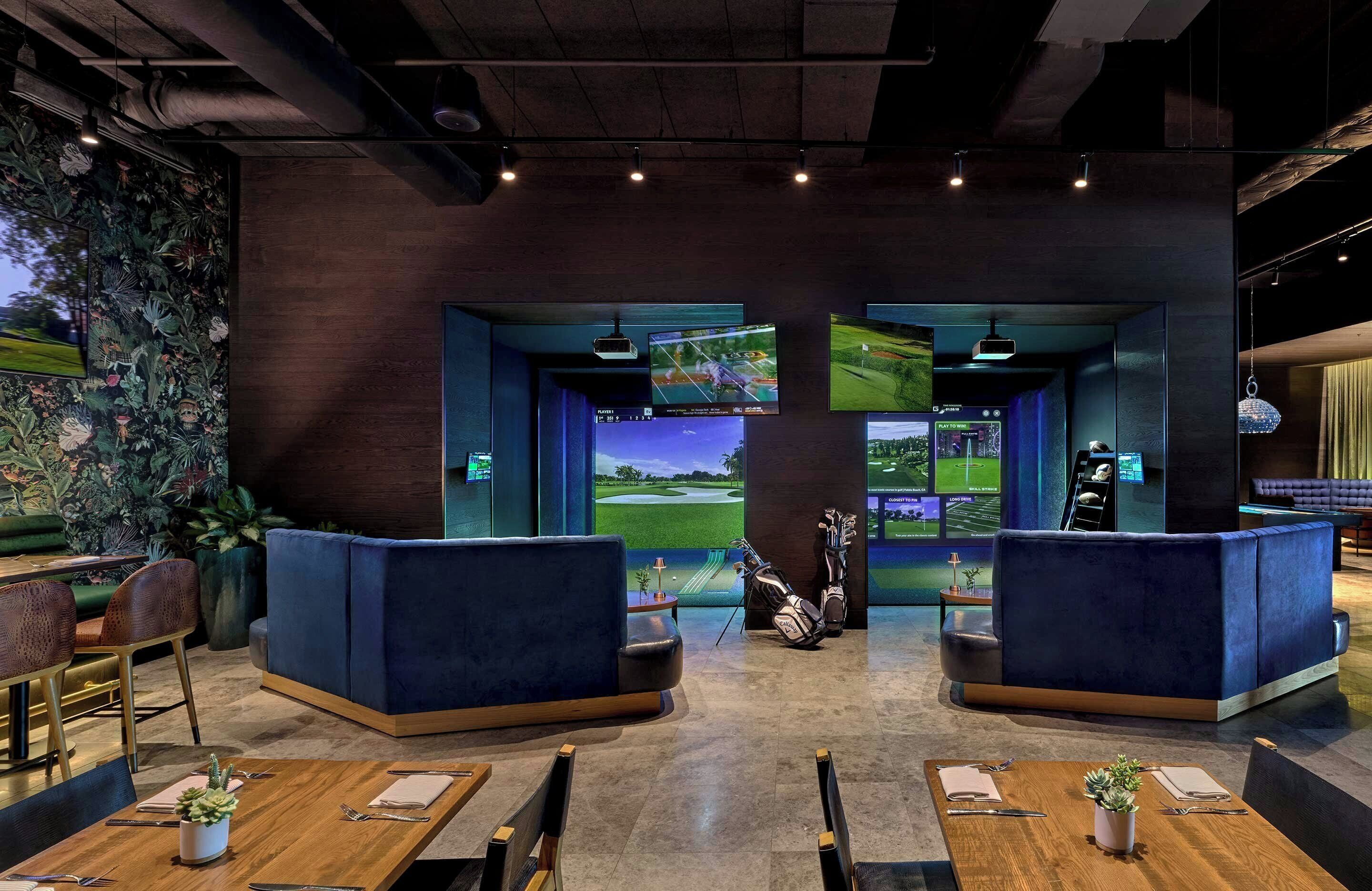 A modern lounge area with seating, a golf-themed decor, and multiple screens displaying golf courses.