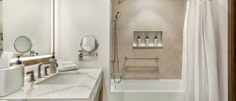 Un baño moderno con lavamanos doble, dos espejos, bañera y ducha.