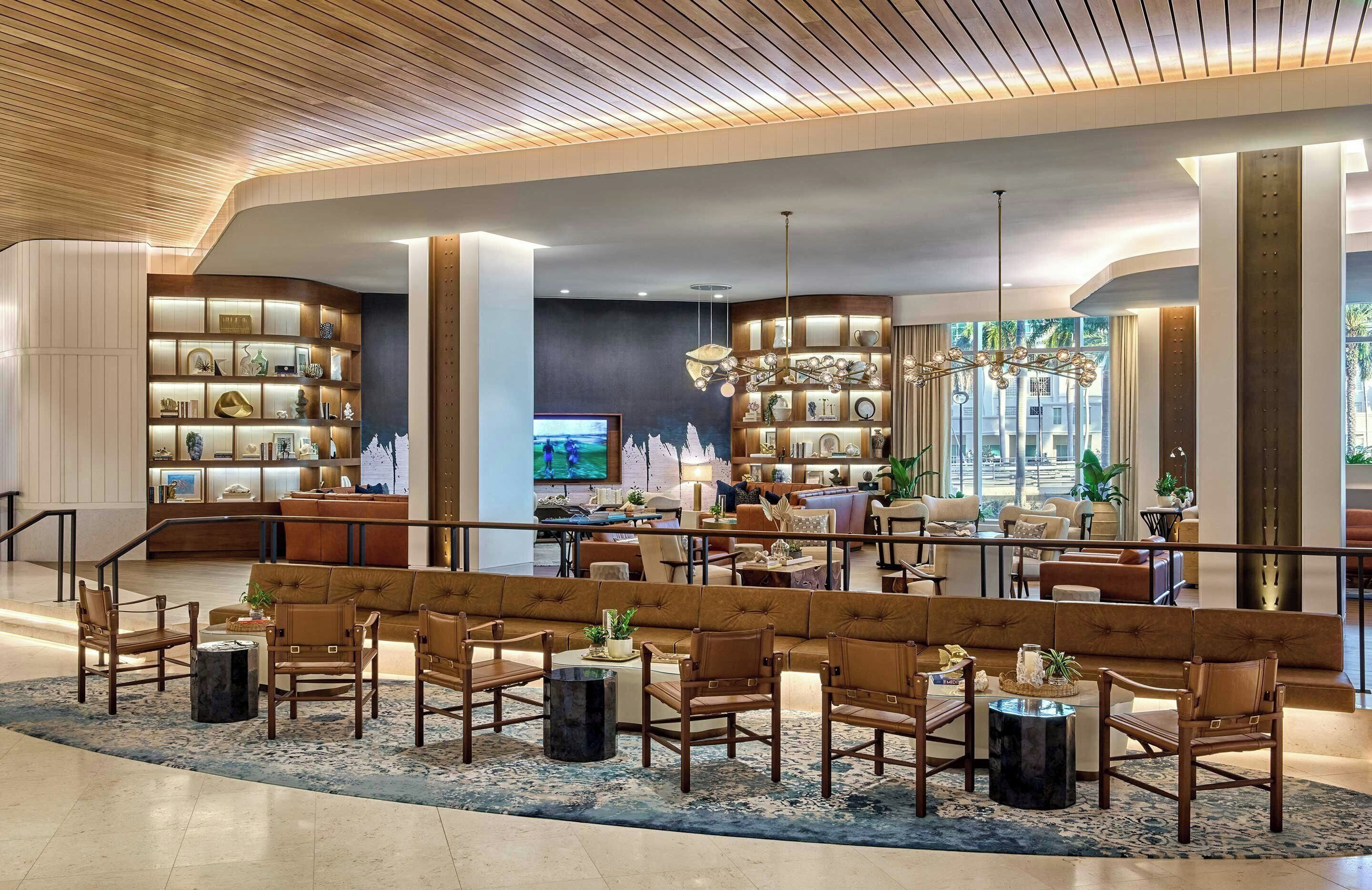 A spacious lobby with a central seating area, a television, and a large window with a view.