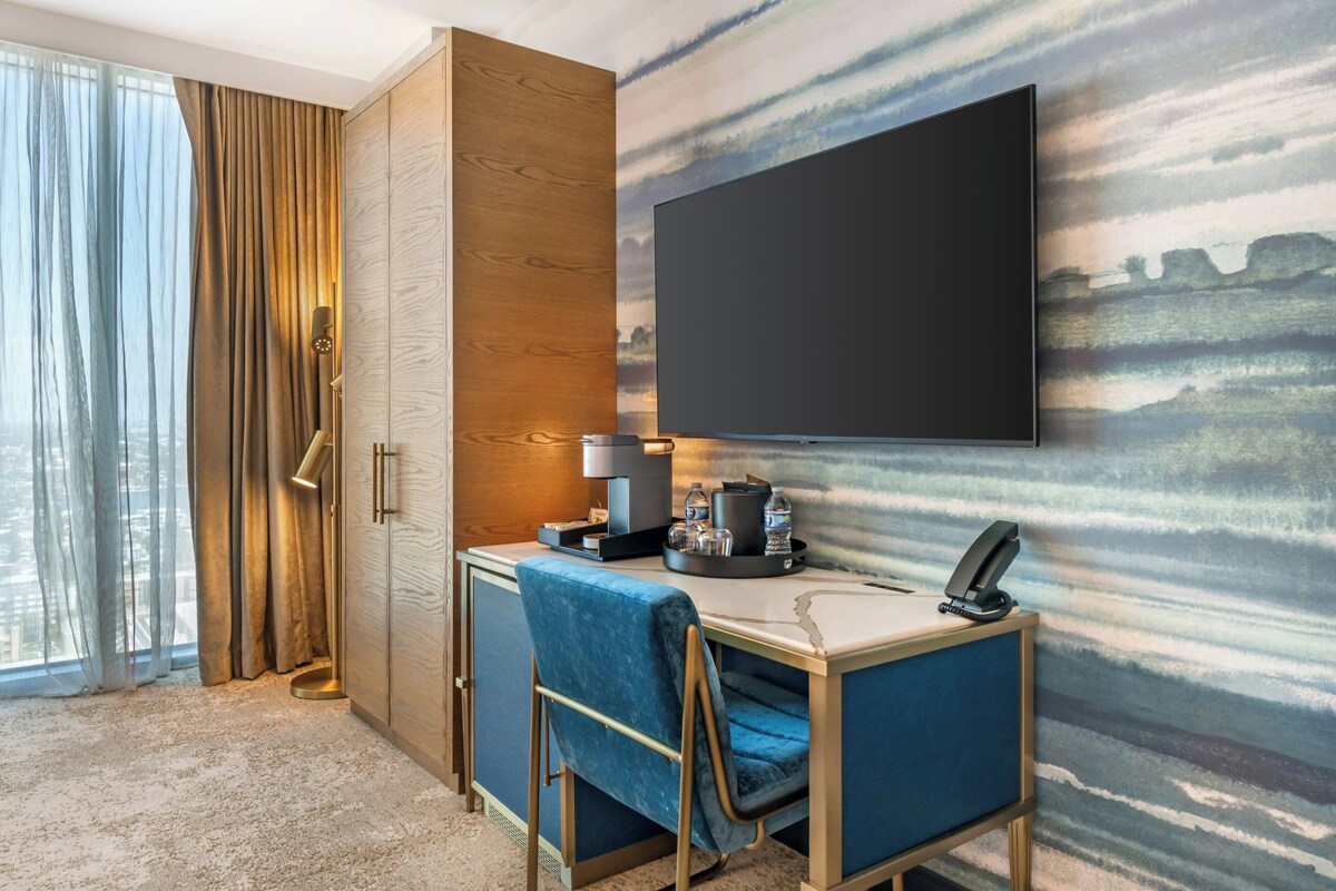Une chambre d’hôtel équipée d’un bureau, d’une chaise, d’une télévision et de rideaux.