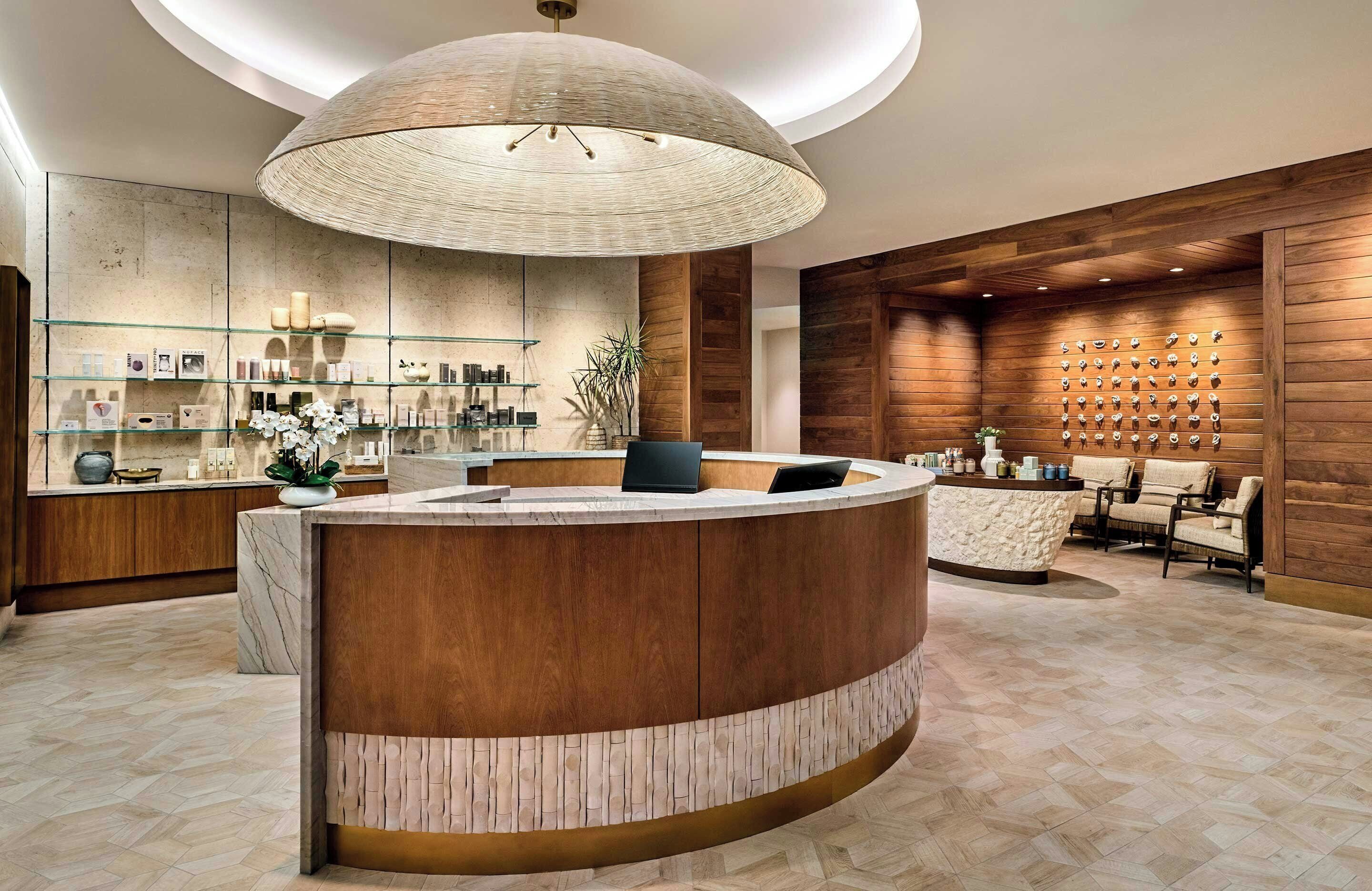 A modern reception area with a curved marble counter, a large woven light fixture, and a wall-mounted display of items.