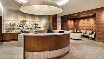 A modern reception area with a curved marble counter, a large woven light fixture, and a wall-mounted display of items.