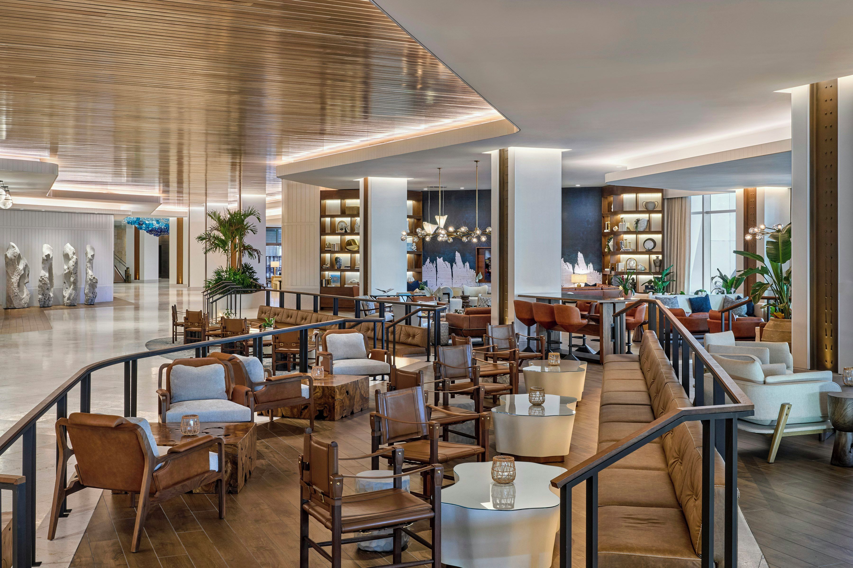 A spacious hotel lobby with multiple seating areas, a central staircase, and a variety of decor.