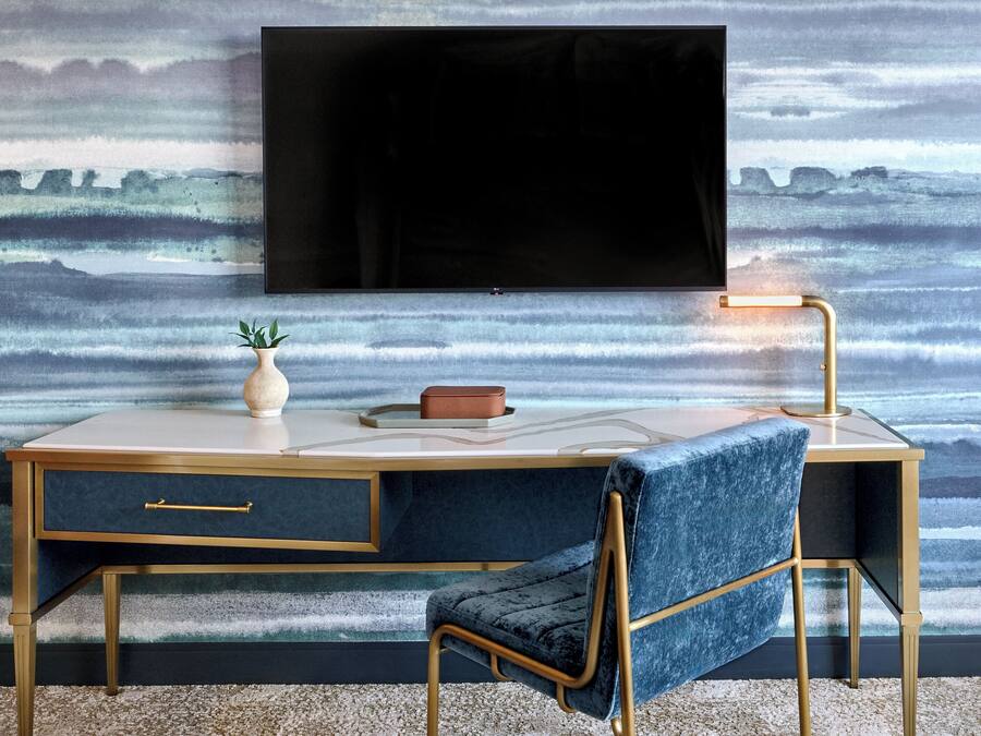A modern desk with a TV mounted above it, a vase, and a book on the desk.
