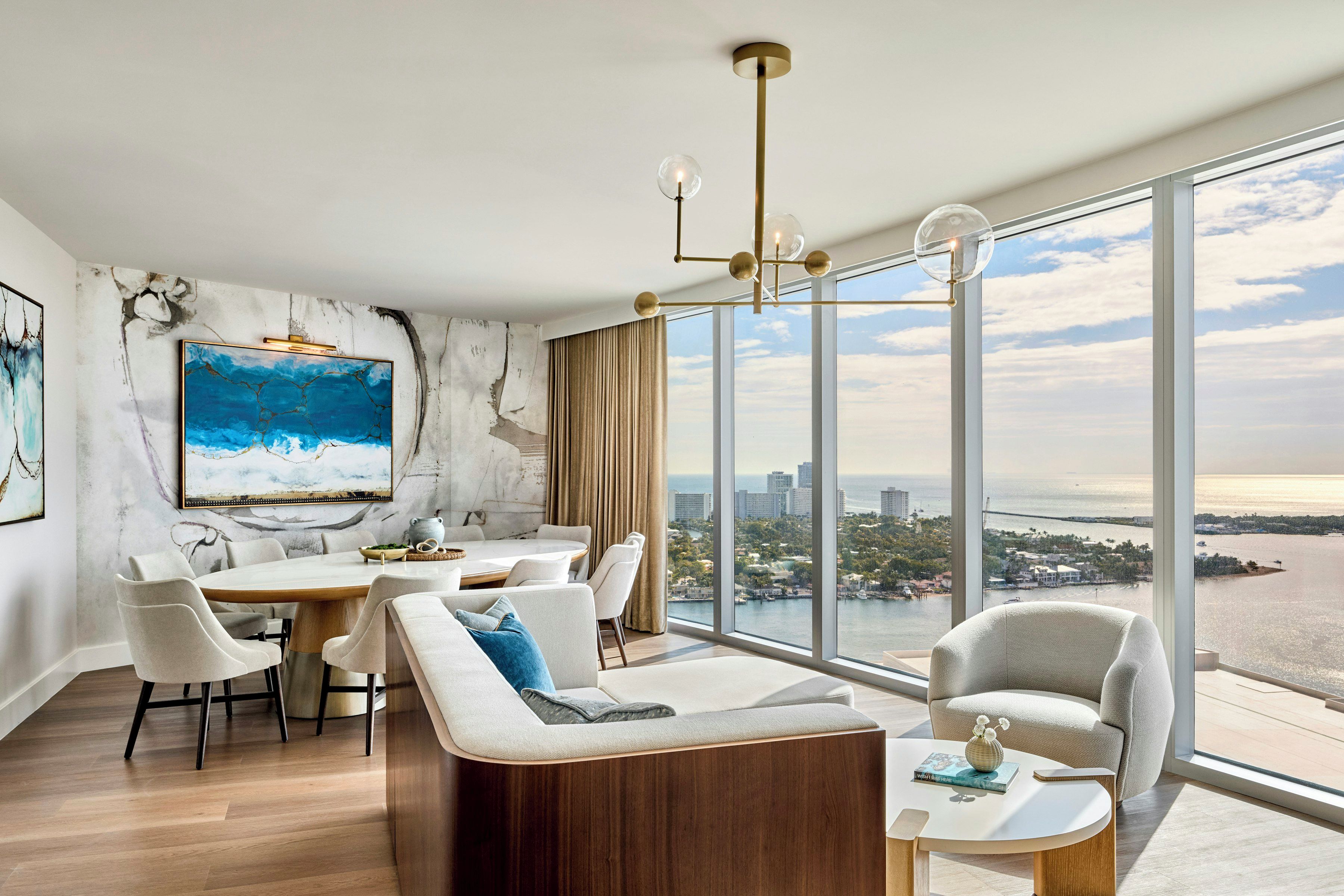 A modern living room with a dining area, large windows, and a city view.