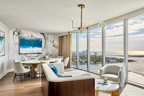 Una sala de estar moderna con comedor, ventanas grandes y vistas a la ciudad.