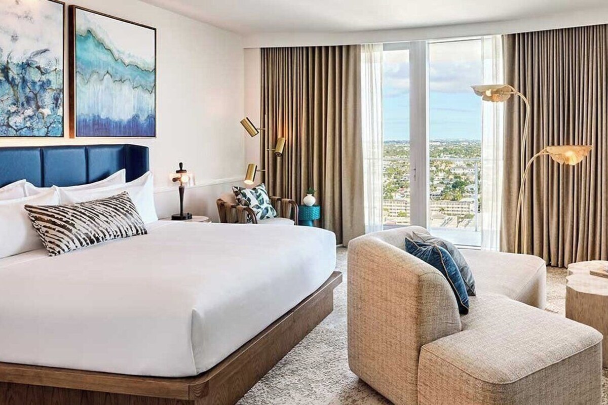 Une chambre d’hôtel avec un grand lit, un canapé, une petite table et une vue sur la ville.