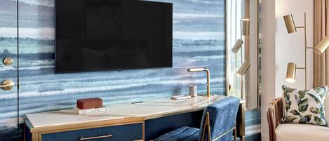 Un dormitorio moderno con una televisión de pantalla plana grande montada en una pared texturizada, una mesita de noche con una lámpara, una silla y un espejo grande.