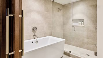A modern bathroom with a freestanding bathtub, a glass-enclosed shower, and a shelf with toiletries.