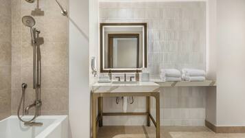 A modern bathroom with a bathtub, shower, vanity with a mirror, and neatly arranged towels.