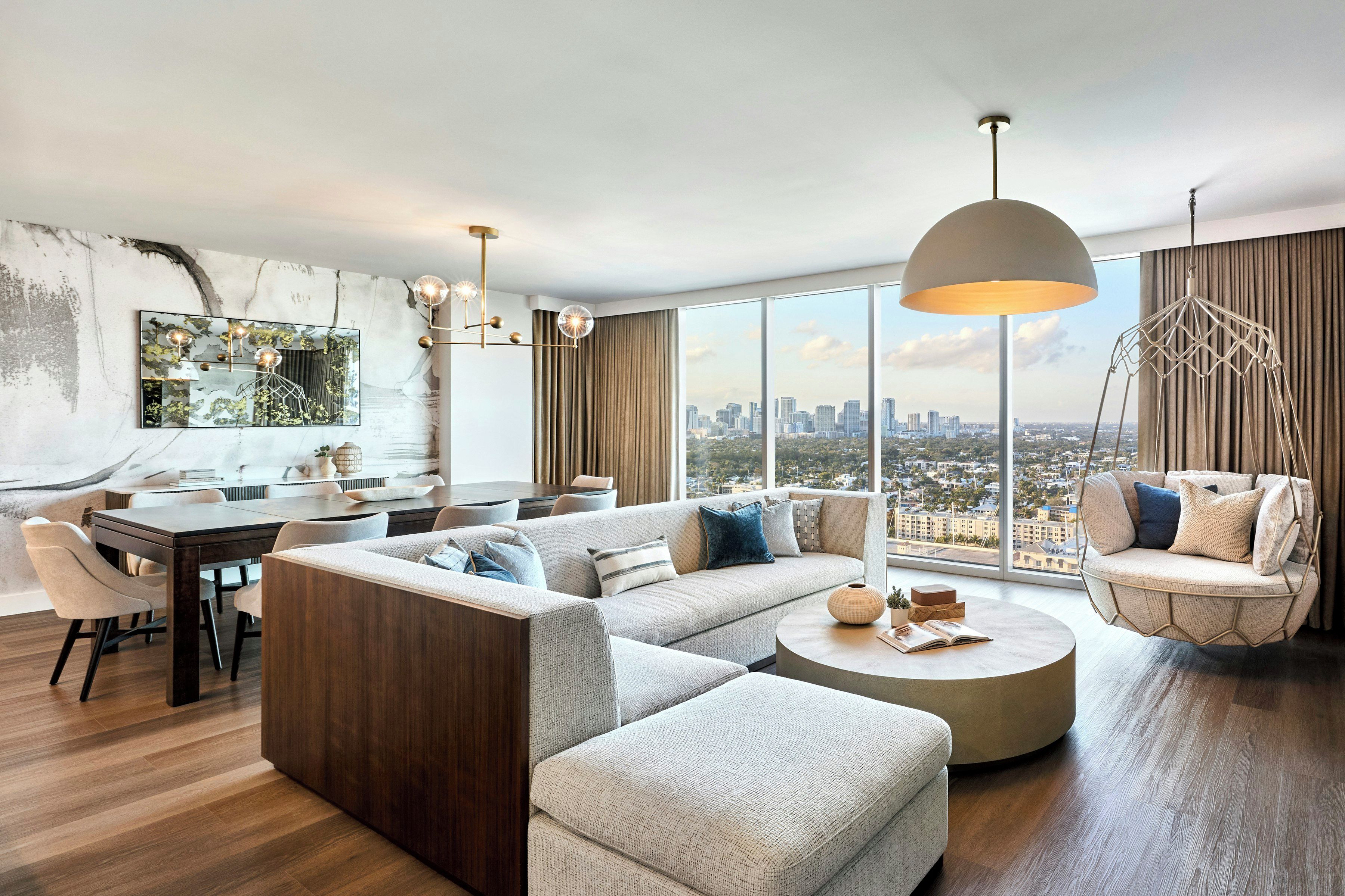 A modern living room with a sectional sofa, a dining area, and a city view.