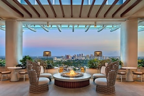 Terraza en la azotea con un brasero, muebles de mimbre y vistas de la ciudad.