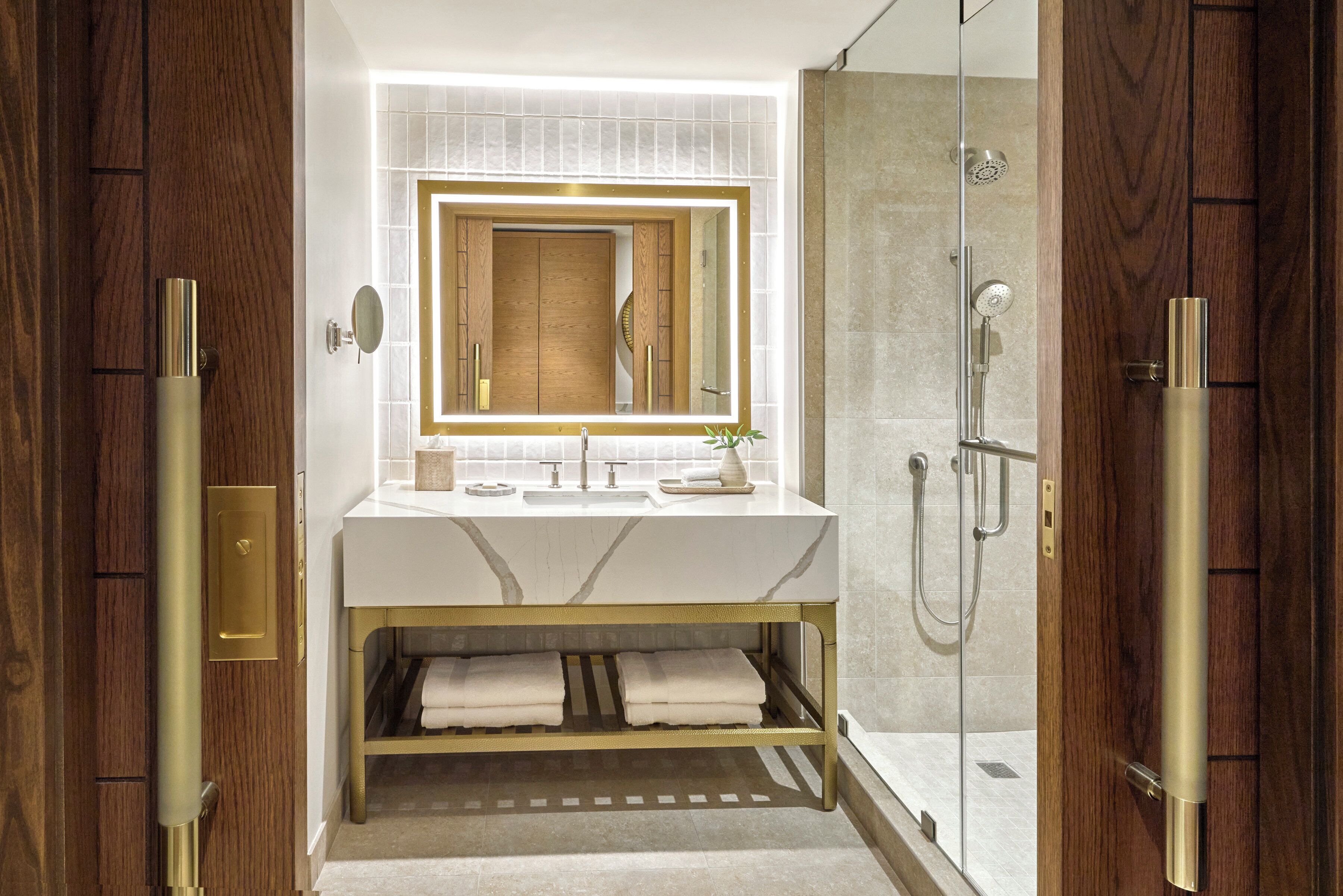 A modern bathroom with a marble vanity, a large mirror, and a shower area.