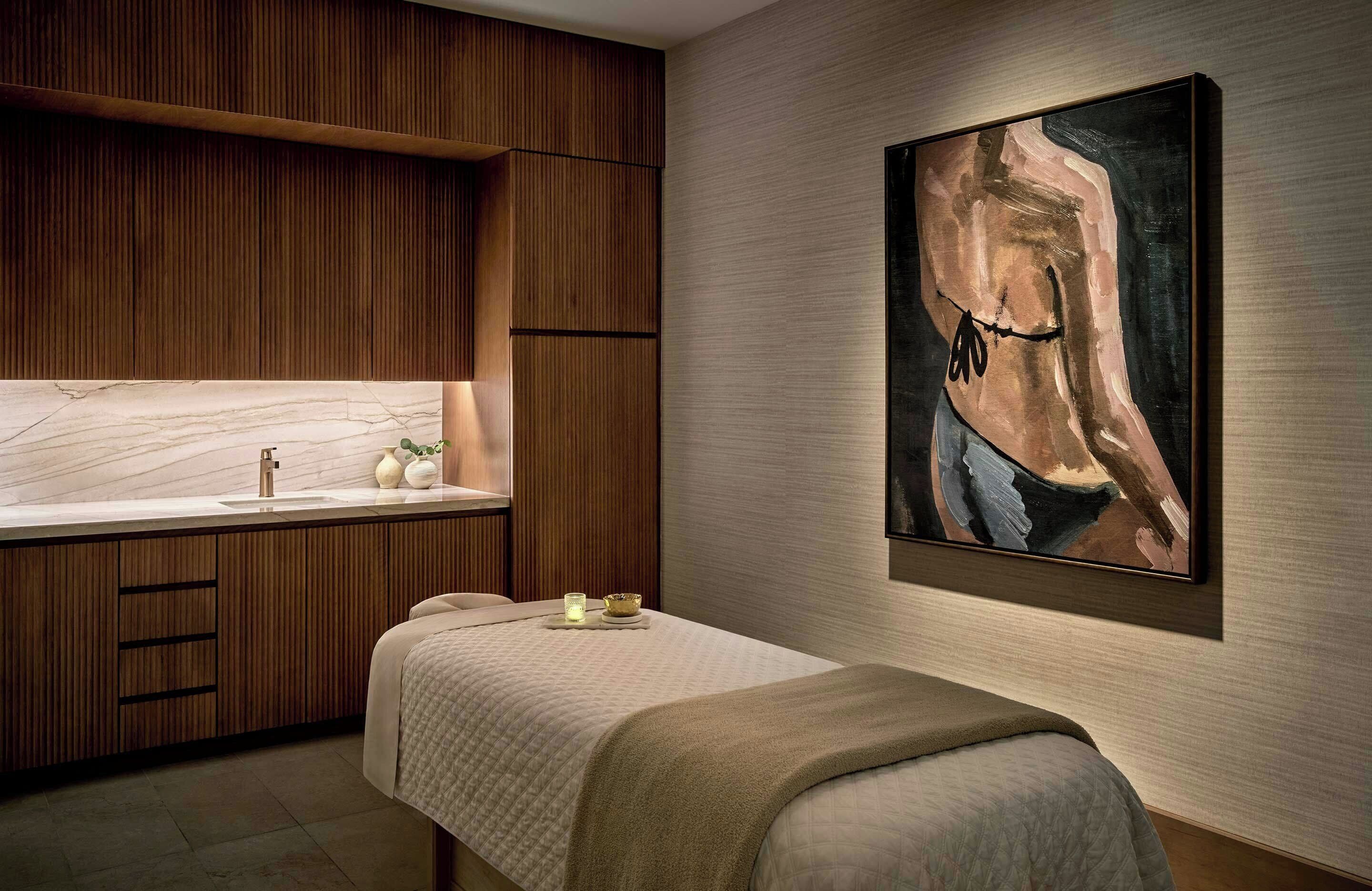 A modern room with a wooden cabinet, a bed, a painting, and a sink.