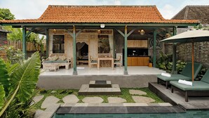 A covered outdoor area with a dining table and chairs, a kitchen, and lounge chairs by a pool. - Kumala Ubud Villa (Ubud)