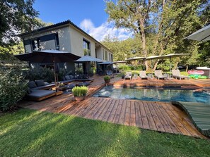 Ein modernes Haus mit Pool, Sitzgelegenheiten im Freien und einem gepflegten Garten.