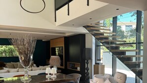 A modern kitchen with a wooden countertop, a white vase with branches, and a set of white cups labeled "Saint Tropez" on the island. - Design house in the heart of the forest Escape & absolute comfort (Roquefort-les-Pins)