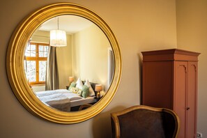 A room with a large round mirror, a bed with pillows, a nightstand, a lamp, and a wardrobe. - Cozy vacation apartment for up to 4 people on the first floor of a manor house (Alt Necheln)