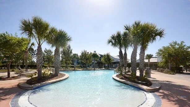 Une piscine dotée d’une terrasse carrelée, entourée de palmiers et de chaises longues.