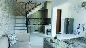 Un espace de vie moderne comprenant un escalier, une cuisine et un canapé agrémenté d’un coussin à motifs.