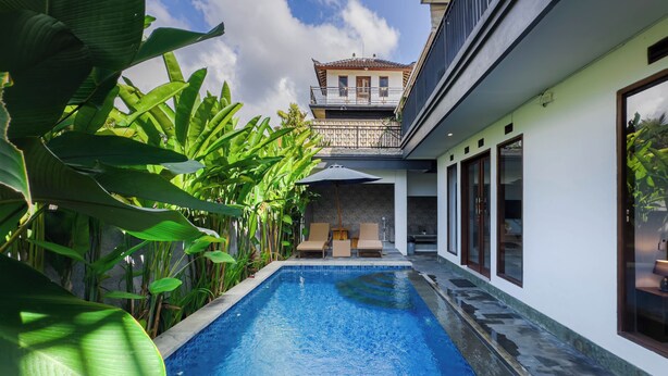 Une piscine offrant une vue sur un bâtiment et une végétation luxuriante.