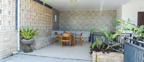 A patio with a table and chairs, potted plants, and a stone wall.