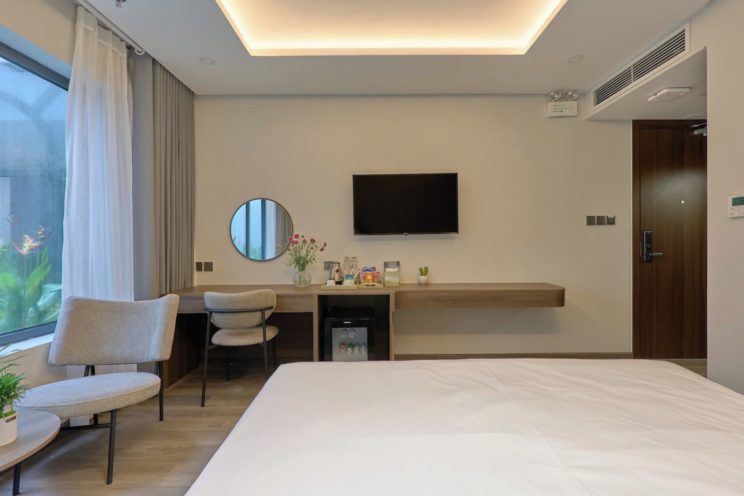 Ein Hotelzimmer mit einem Bett, einem Schreibtisch mit Stuhl, einem Fernseher und einem kleinen Kühlschrank.