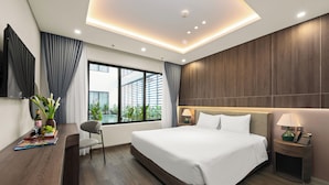 Une chambre d’hôtel moderne dotée d’un grand lit, d’un bureau avec une chaise, d’une télévision et d’une fenêtre avec des rideaux.