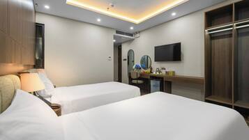 A hotel room with two beds, a desk with a chair, a television, and a wardrobe.