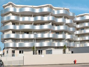 A multi-story building with a unique wavy architectural design, featuring balconies on each floor. - Odalys Référence Le Lotus Blanc by Interhome (Le Barcarès)