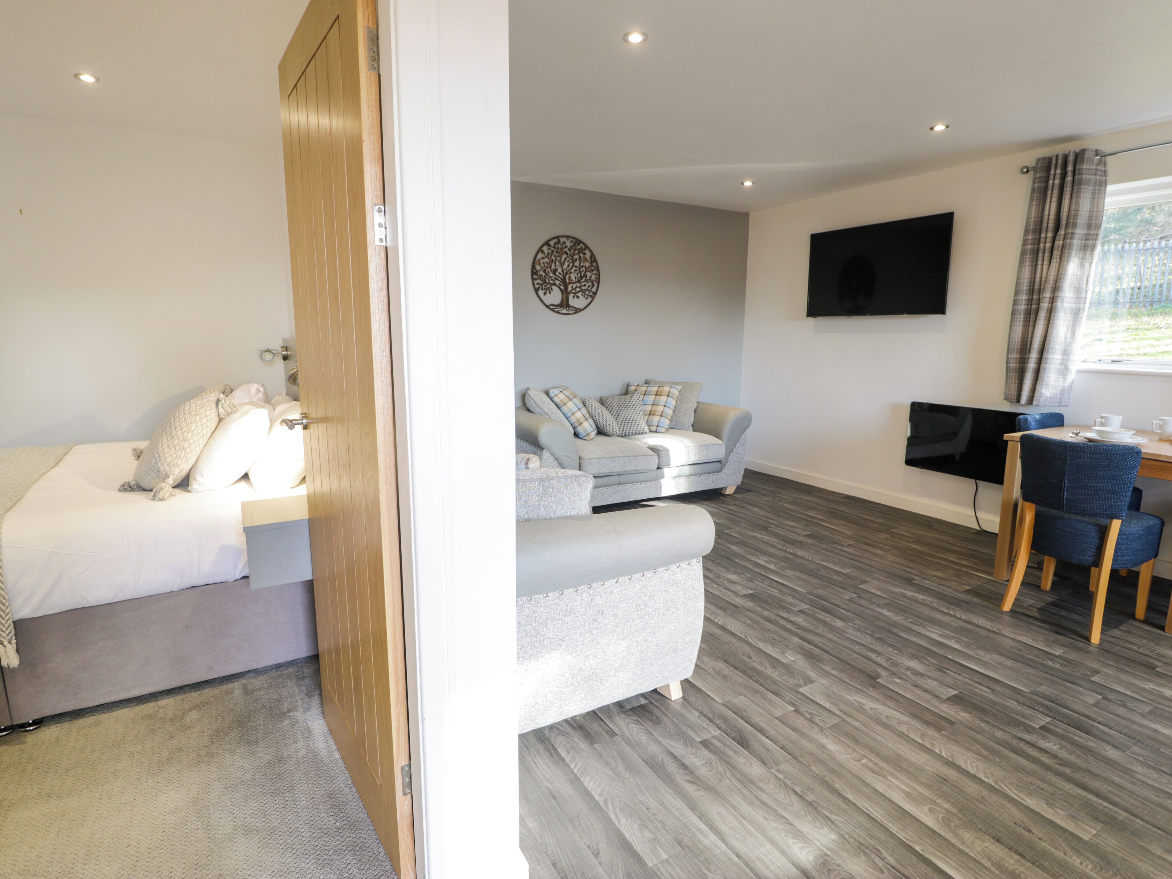 Een moderne kamer met een bed, een slaapbank, een bureau en een televisie.