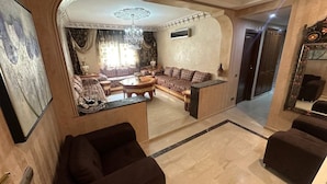 Un amplio salón con un conjunto de sofás, una mesa de centro y un espejo decorativo.