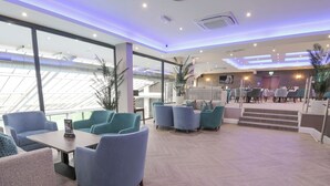 A modern hotel lobby with seating areas, a reception desk, and a staircase leading to upper floors. - Classic Lodge 38 (Rhyl)