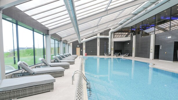 An indoor swimming pool with lounge chairs and a glass ceiling. - Classic Lodge 38 (Rhyl)