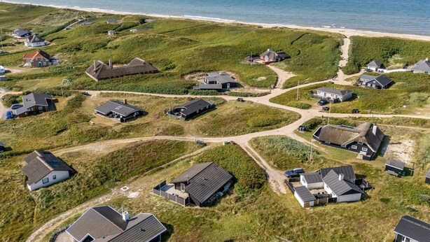 Vue aérienne d’une zone résidentielle côtière, avec des maisons et une plage.