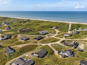 Vue aérienne d’une zone résidentielle côtière, avec des maisons et une plage.