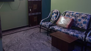 Una sala de estar con un sofá, una mesa de centro, un televisor montado en la pared y una puerta con un panel decorativo.