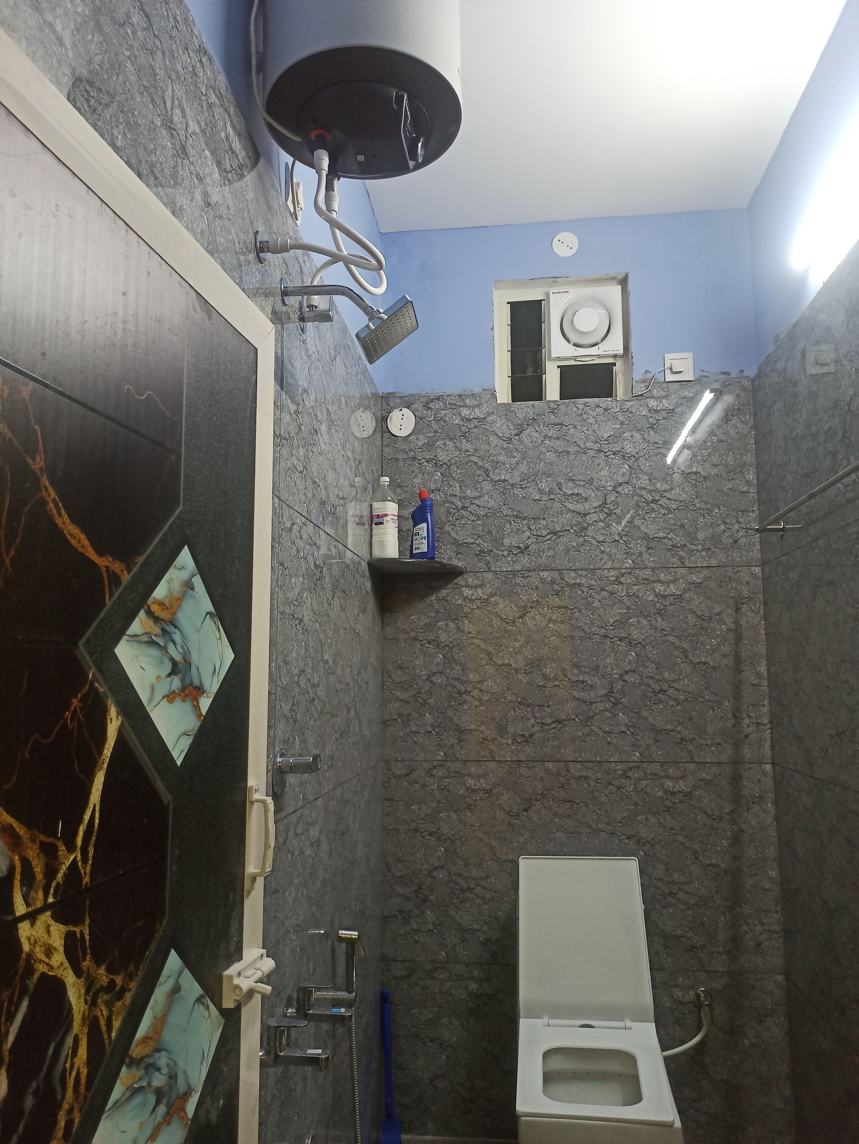 A bathroom with a shower, toilet, and a small shelf with toiletries.