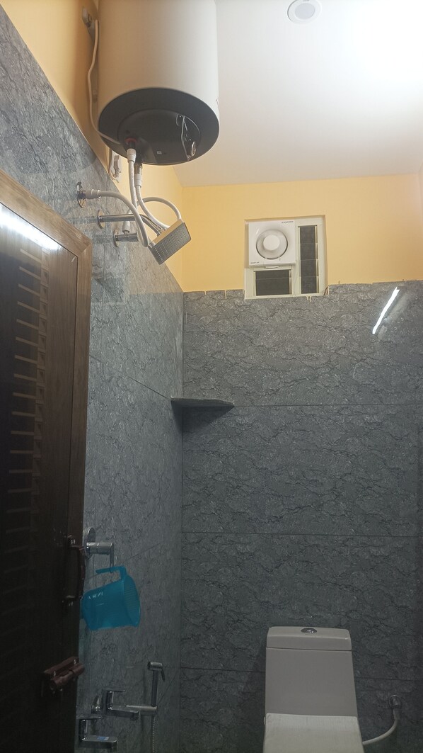 Un baño con ducha, inodoro, toallero y calentador de agua.