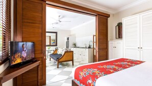 A hotel room with a bed, a television, a dining area, and a kitchen. - Villa Zita (Seminyak)