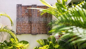 A wall with intricate patterns and tropical plants. - Villa Zita (Seminyak)
